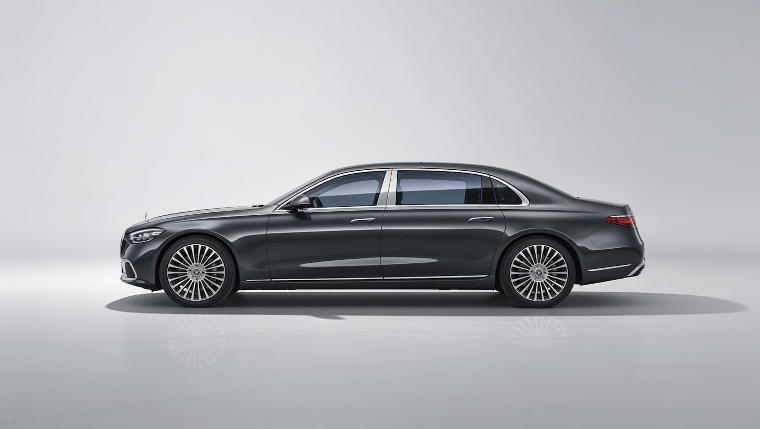 A dark metallic sedan with chrome trim, photographed against a plain pale backdrop